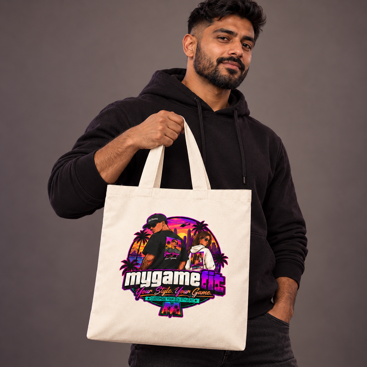 Natural canvas tote held by a bearded South Asian man on a warm gray studio background